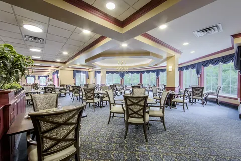 Dining room with upholstered chairs, tall windows and a chandelier