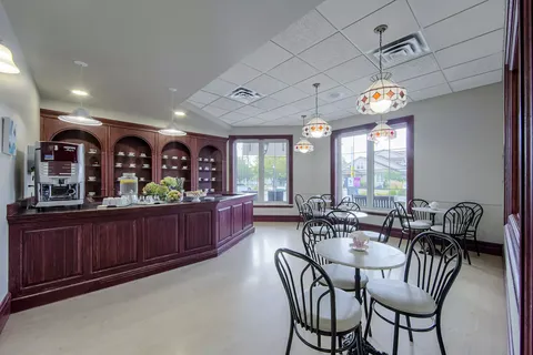 Room with round tables and chairs beside a dark wooden counter