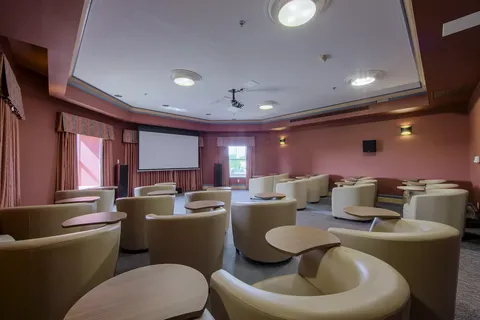 Room with armchairs and small tables facing a blank projection screen