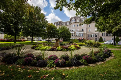 Residence building behind landscaped garden beds and mature trees