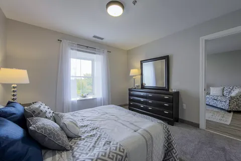 Bedroom with a made bed, a dresser and a large wall mirror
