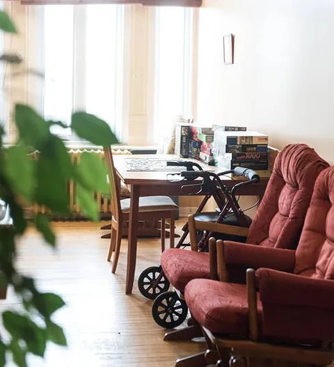 Room with an armchair, tables, chairs and large windows