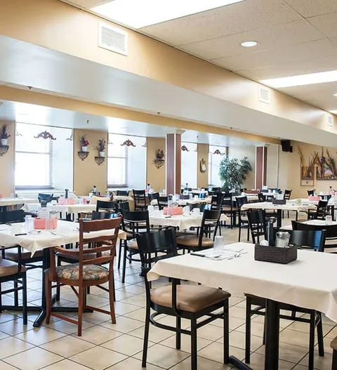 Dining room with long tables, dark chairs and large mirrors