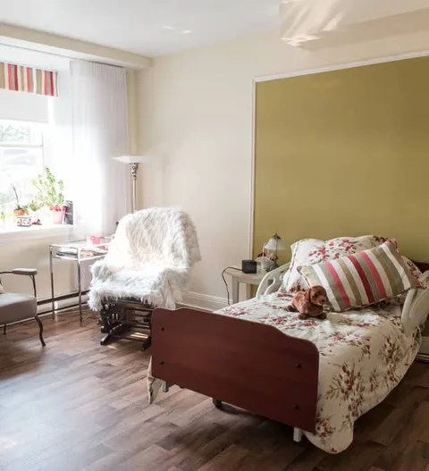 Bedroom with a bed and chairs beside a curtained window
