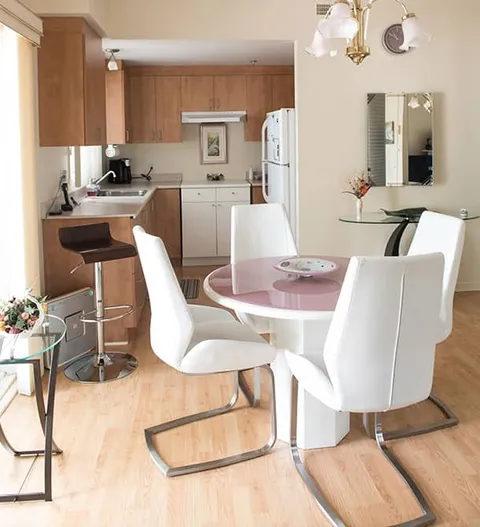 Room with a round dining table, chairs, a wall mirror and a kitchen area