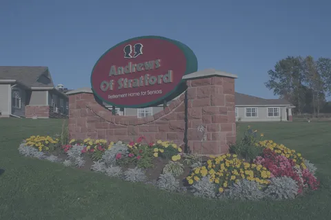 Residence sign in a flower bed with a low-rise building behind it