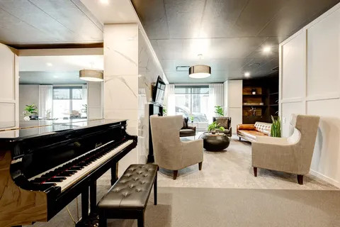 Lounge with a grand piano, upholstered chairs and a fireplace
