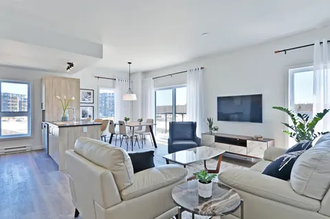 Sitting area with a sofa, armchair, television and dining table near windows