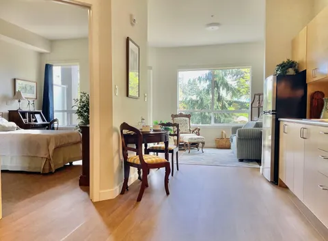 Suite with bedroom doorway, dining table, kitchenette and a sitting area.