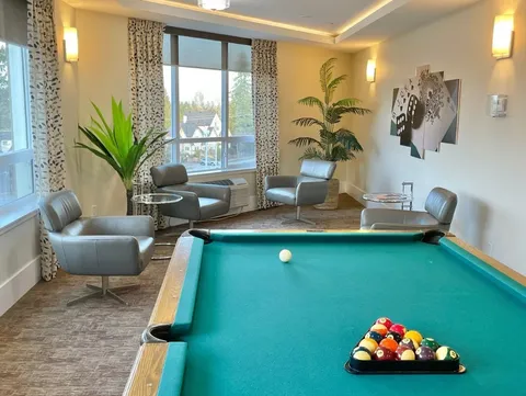 Billiards room with a pool table and seating beside windows.