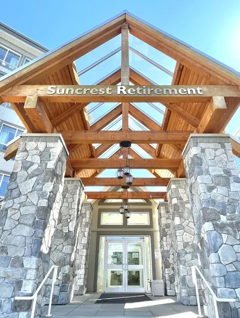 Covered entrance with timber beams, stone columns and glass doors.