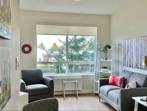 Lounge with armchairs, side tables and large windows.