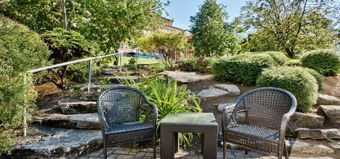 Garden seating beside stone steps, shrubs and trees