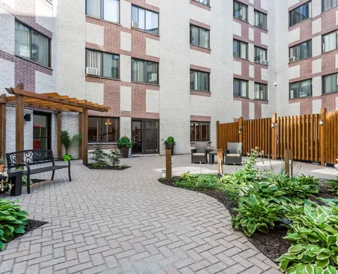 Residence exterior beside a courtyard with benches and garden beds