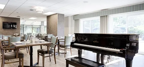 Common area with a piano and tables beside large windows