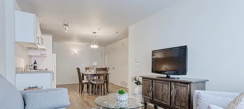 Suite living and dining area beside a white kitchen