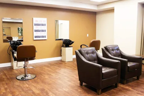 Salon with styling chairs, two shampoo basins, mirrors and waiting armchairs