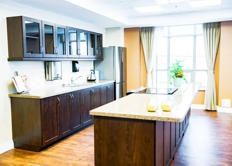 Kitchen with dark wooden cabinets, an island, a sink and a stainless steel refrigerator