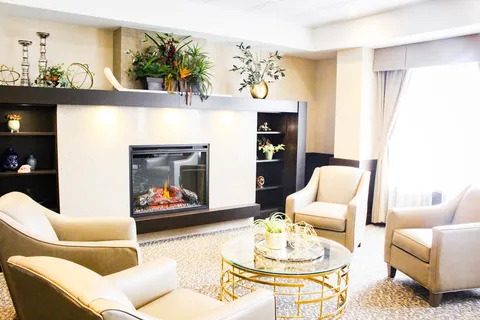 Sitting area with cream armchairs, a glass coffee table and a fireplace