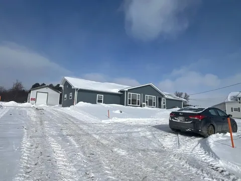 Single-storey residence and garage beside a snow-covered driveway.