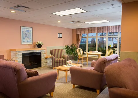 Lounge with armchairs, fireplace and tables.