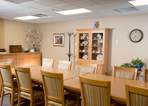 Dining table beside a display cabinet and serving counter.
