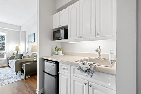 Kitchenette with white cabinets, microwave and refrigerator