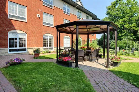 Gazebo with chairs beside a brick building and lawn