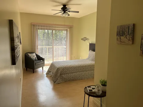Bedroom with a bed, armchair, ceiling fan and patio door