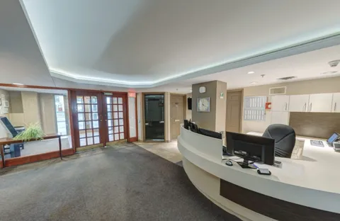 Curved reception counter beside glass entrance doors and a corridor