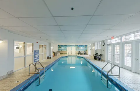 Indoor swimming pool with handrails, tiled surrounds and windows