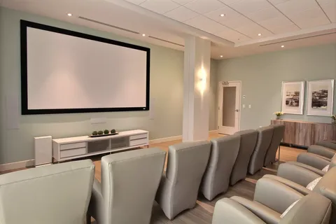 Screening room with grey recliners and a blank projection screen