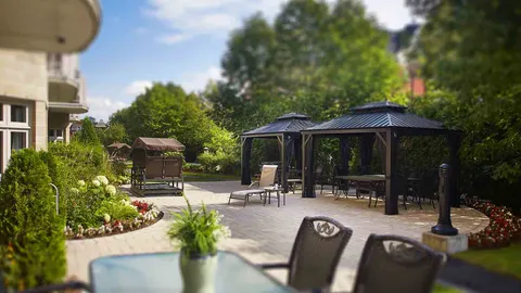 Garden patio with gazebos, chairs, a swing and planted borders