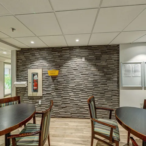 Room with round tables, wooden chairs and a stone-patterned wall