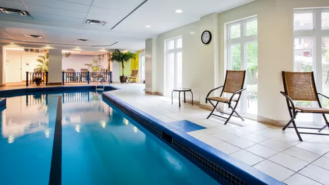 Indoor pool beside windows and wicker chairs