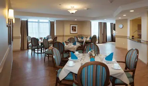 Dining tables with blue chairs, white tablecloths and folded napkins