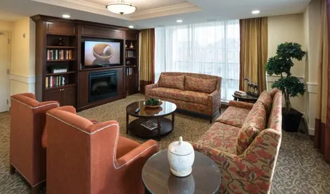 Sofas and armchairs facing a fireplace and a television showing a coffee cup
