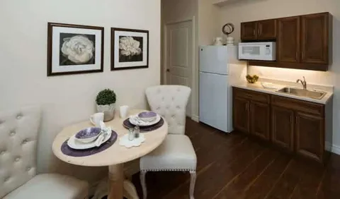 Small table and two chairs beside a kitchenette with dark cabinets