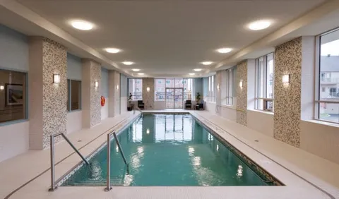 Indoor pool with metal handrails and a row of tall windows