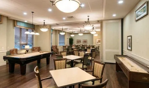 Billiards table beside tables, chairs and a counter in a bright room
