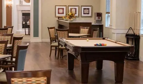 Billiards table beside tables, chairs and a kitchenette