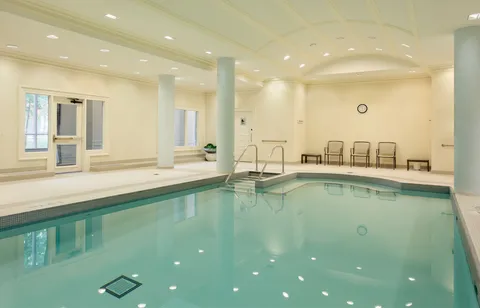 Indoor swimming pool with entry steps and poolside seating.