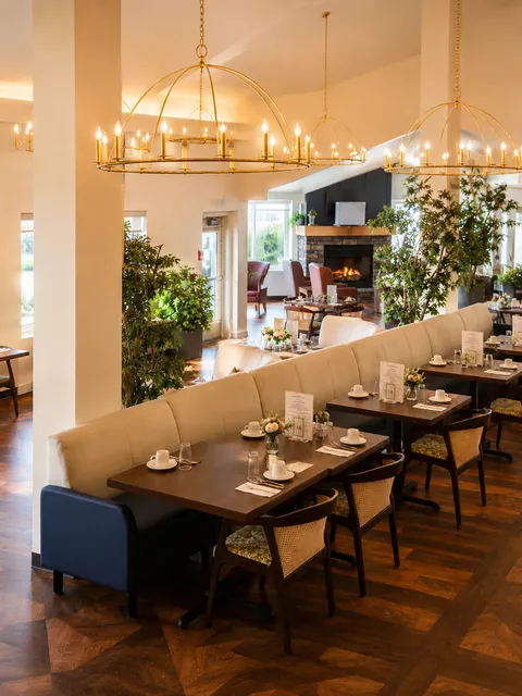 Dining room with tables, banquette seating and chandeliers.