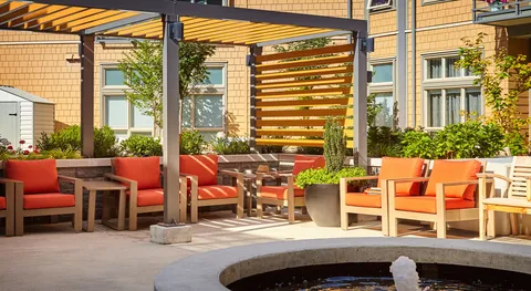 Courtyard patio with orange seating, timber pergola and fountain.