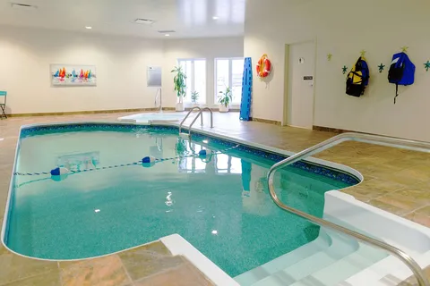 Indoor swimming pool with handrails and a tiled deck.