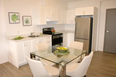 Suite kitchen with white cupboards and a glass dining table.