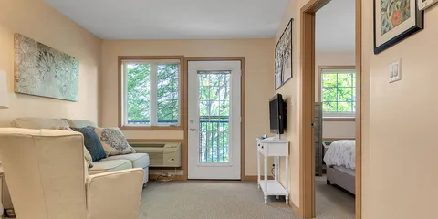 Sitting area with a sofa, television and glass door, with a bedroom beyond