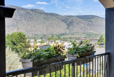 Balcony railing with flower boxes overlooking nearby buildings and hills