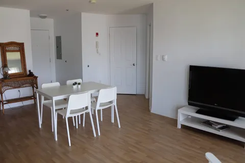 Room with a white dining table and chairs, a wicker console, a mirror and a television