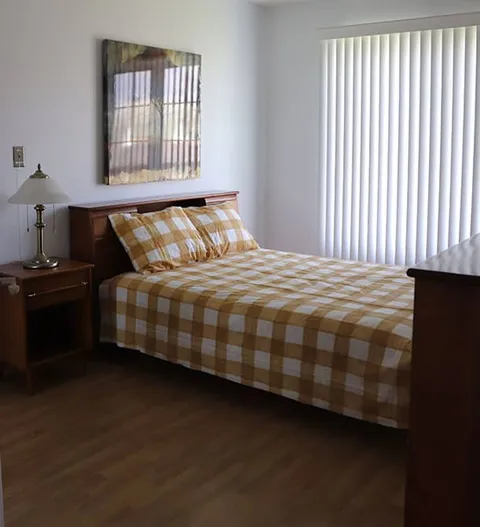 Bedroom with a checked bedspread, a chest of drawers and a window